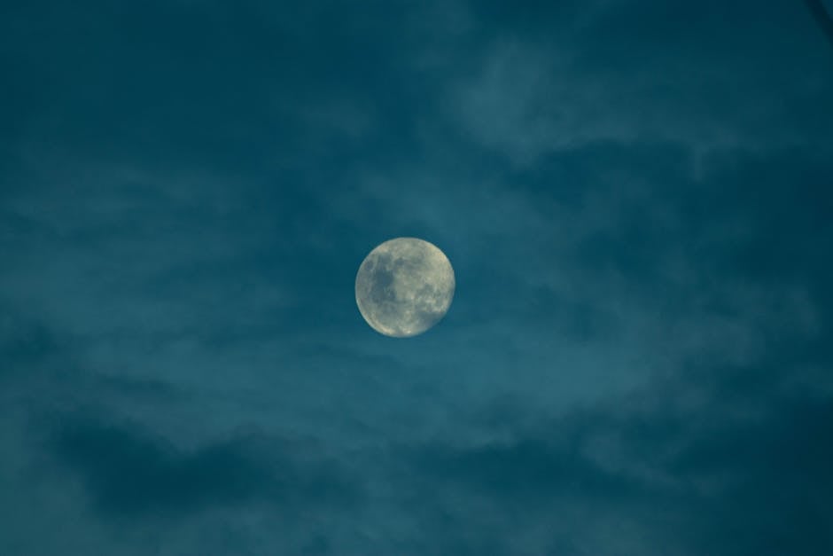 A full moon shining through a cloudy night sky, creating a serene and mystical atmosphere.