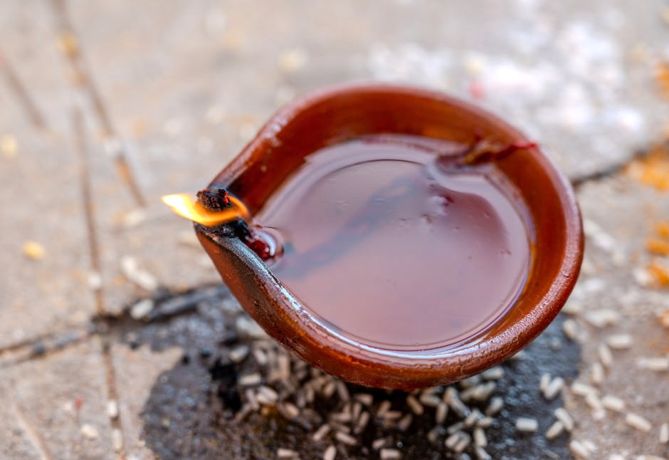 Close-up of a lit clay diya with oil, used in festivals and ceremonies.