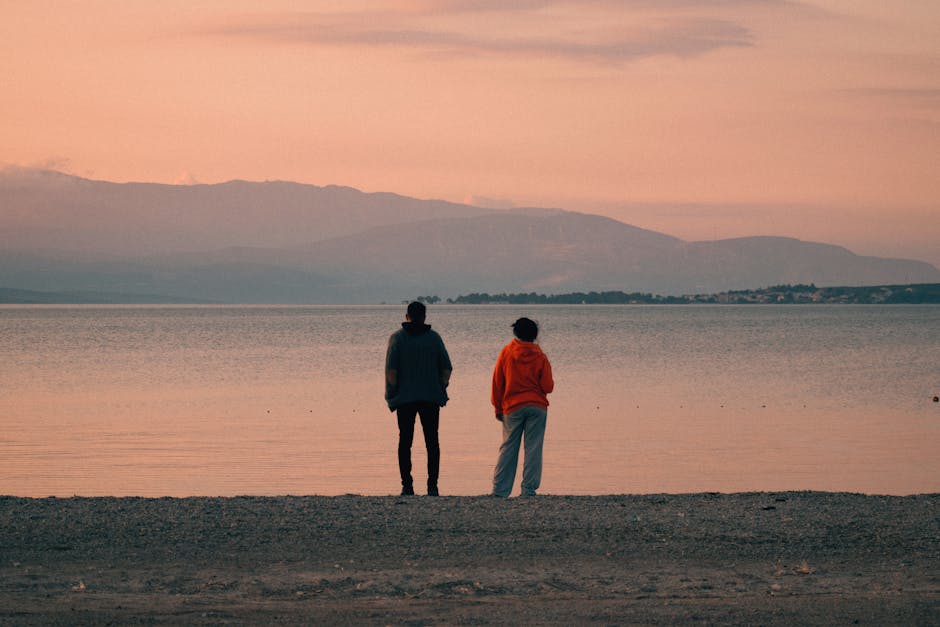 Two people on the beach at sunset in Urla, İzmir, Türkiye, enjoying a tranquil seaside view.