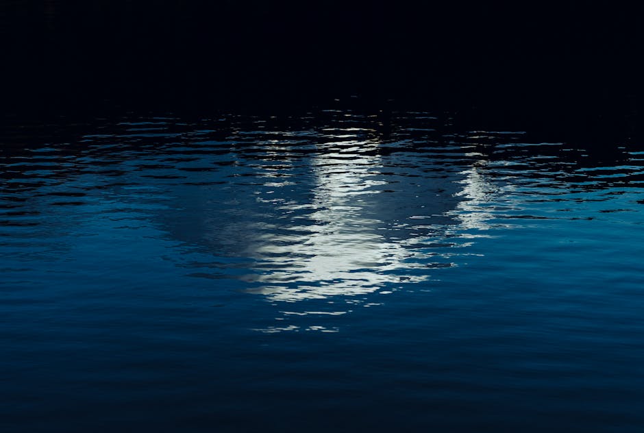 Calm water reflecting a nighttime scene with gentle ripples and dark tones.