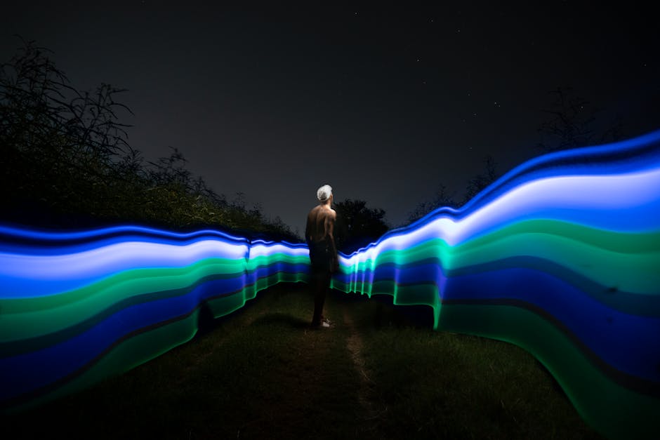 Captivating nighttime scene with light trails and a person standing in a field, showcasing long exposure artistry.