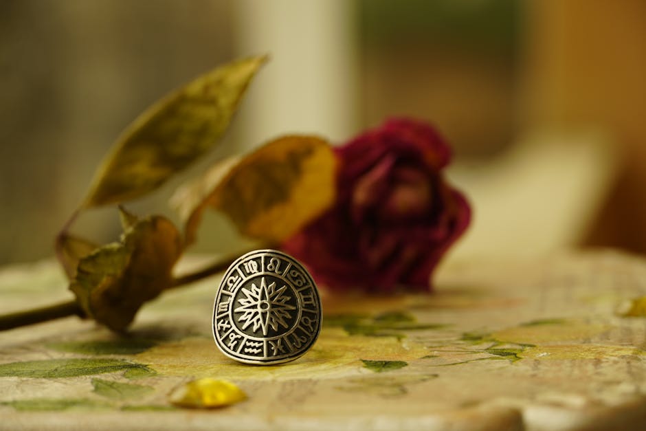 Close-up of a zodiac-themed ring with dried flowers in a warm, artistic setting.