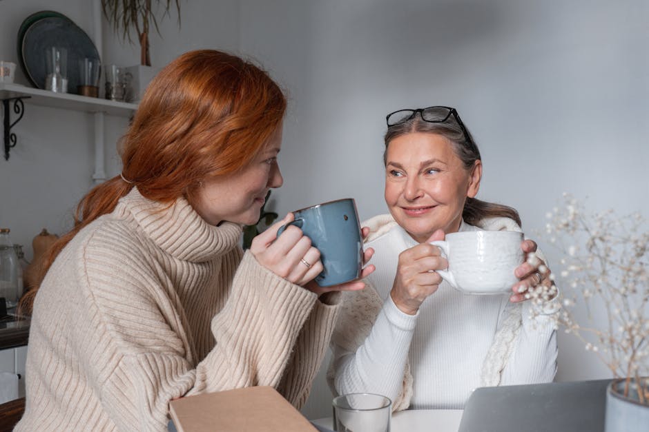 Two women enjoying a relaxing moment with coffee, sharing smiles and warmth indoors.