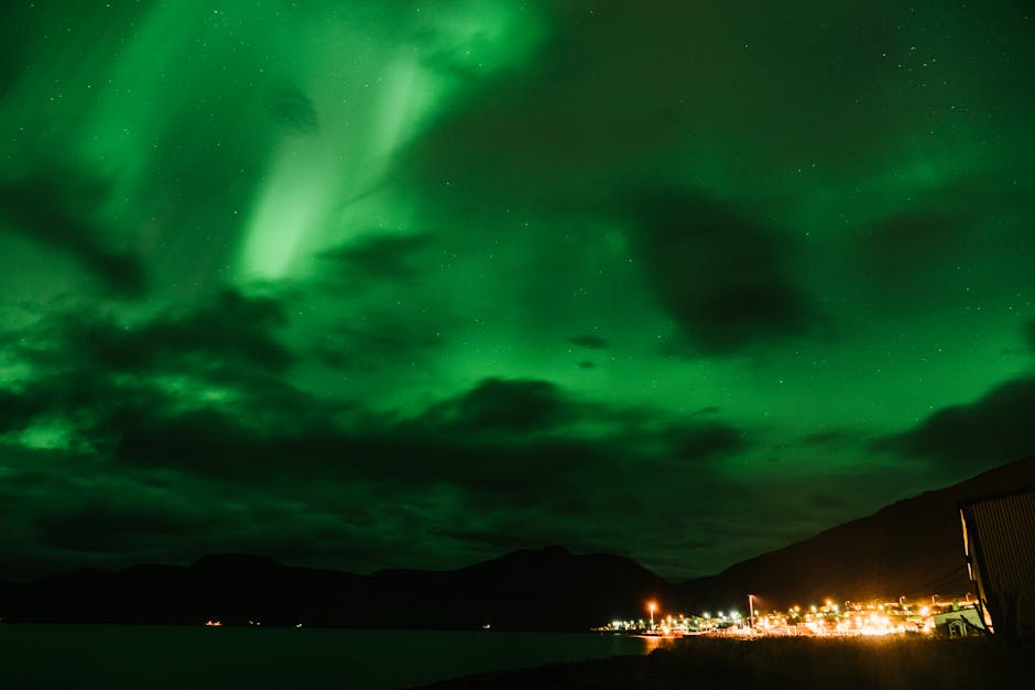 Magnificent Northern Lights glowing brightly over a tranquil coastal town at night.