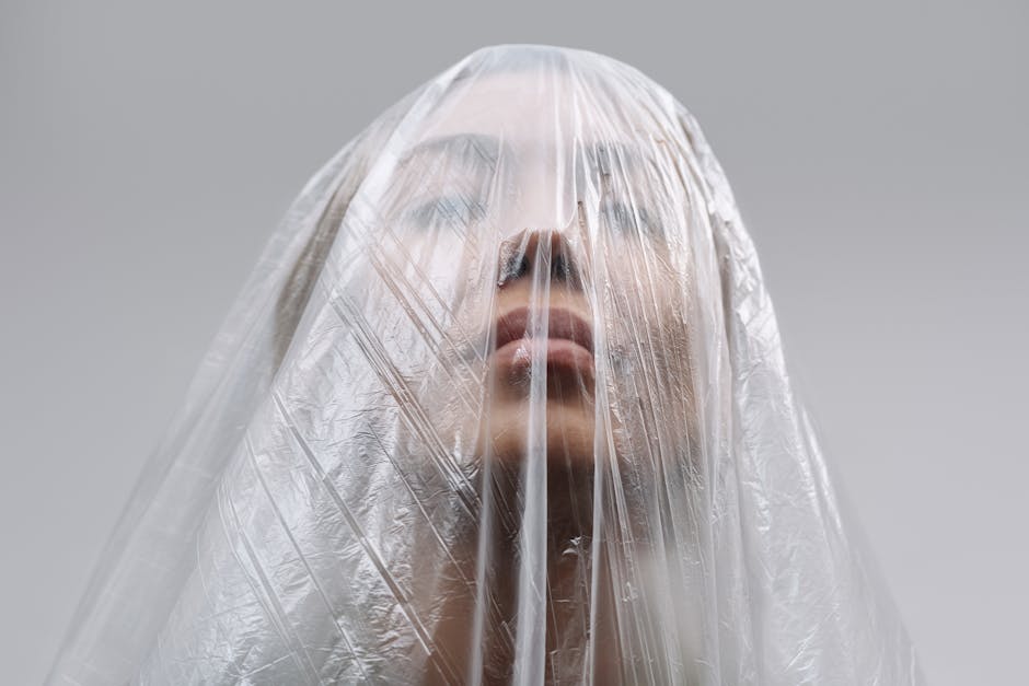 Close-up of a woman wrapped in plastic, symbolizing modern isolation and environmental themes.