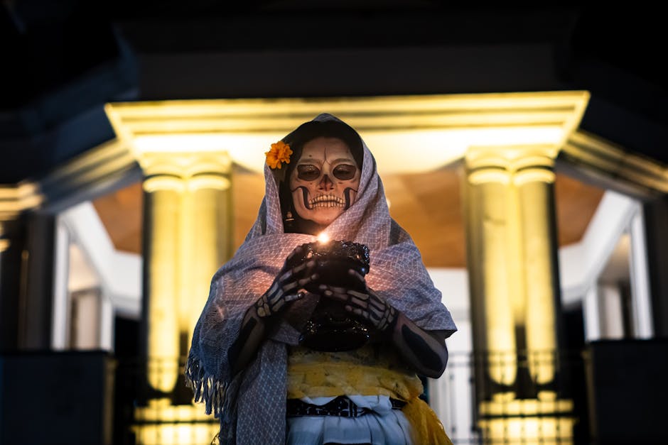 A person dressed as a Catrina holding a candle during a Day of the Dead celebration.