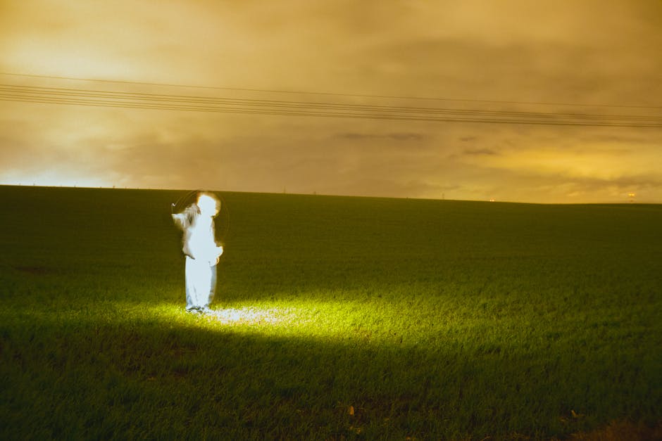 Mystical scene with a glowing figure in a rural nighttime field, creating an ethereal atmosphere.