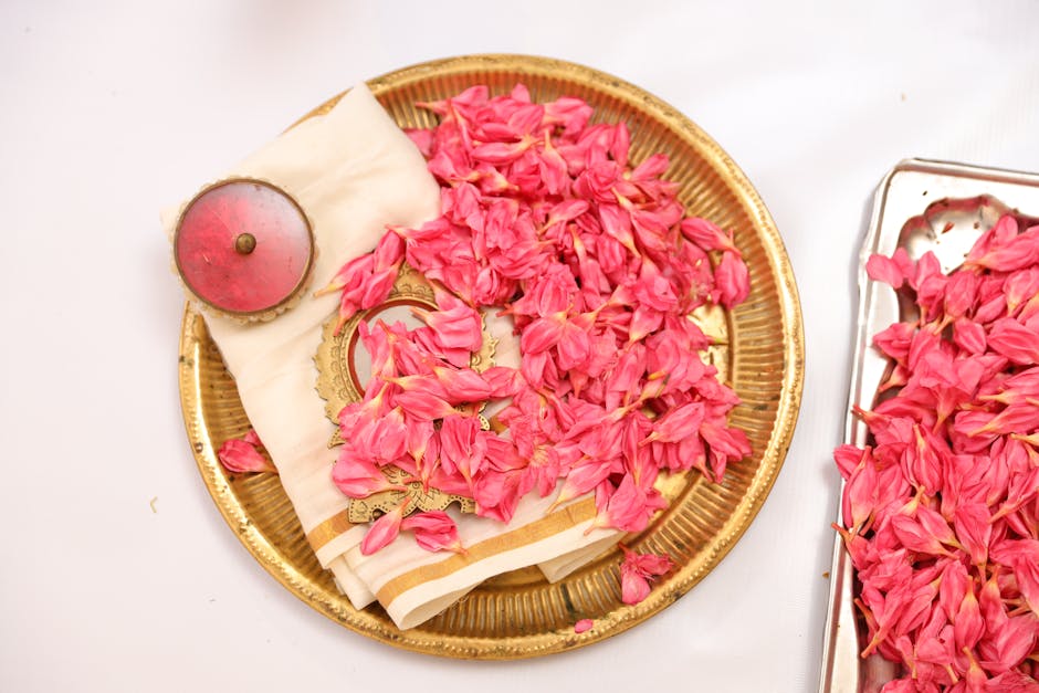 Aesthetic display of pink flower petals on a golden tray with a napkin over white background.