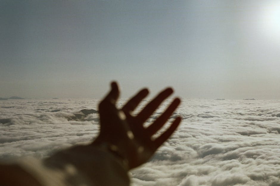 A silhouetted hand reaches towards a cloudy sky, creating a sense of adventure and exploration.