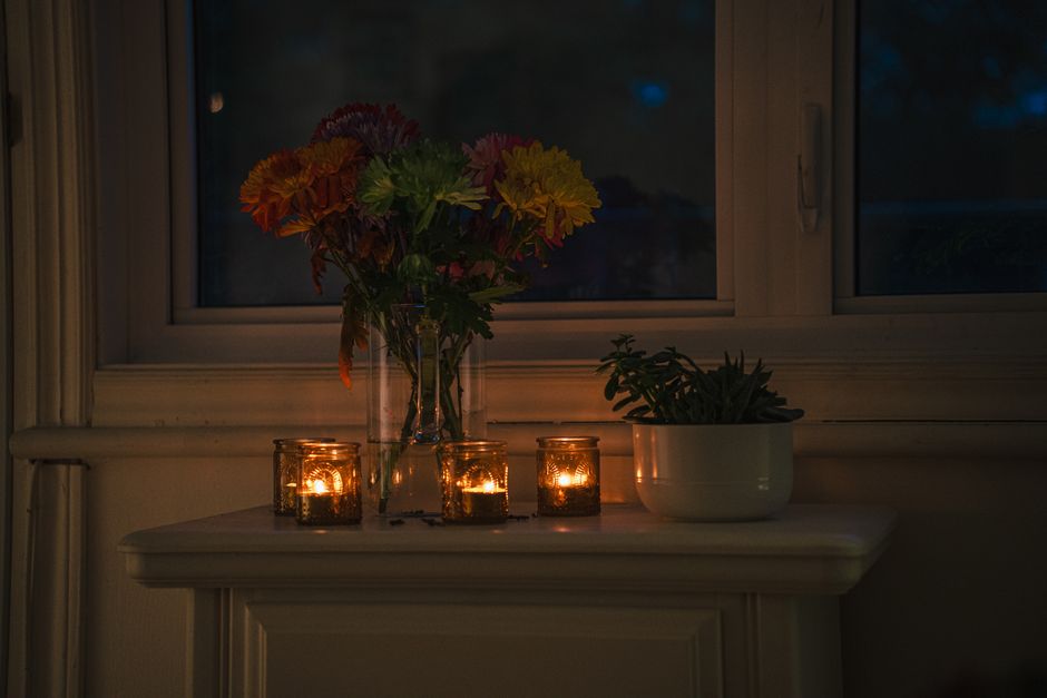 A warm, candlelit ambiance with vibrant flowers on a windowsill, creating a serene night scene.
