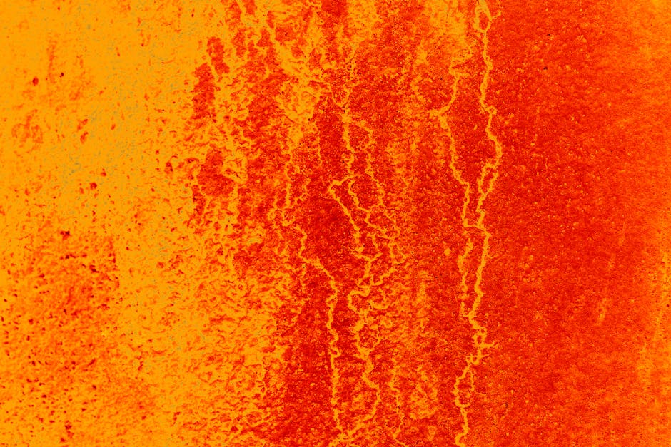 Dynamic abstract texture in vibrant orange and red tones, resembling flowing lava or a fiery landscape.