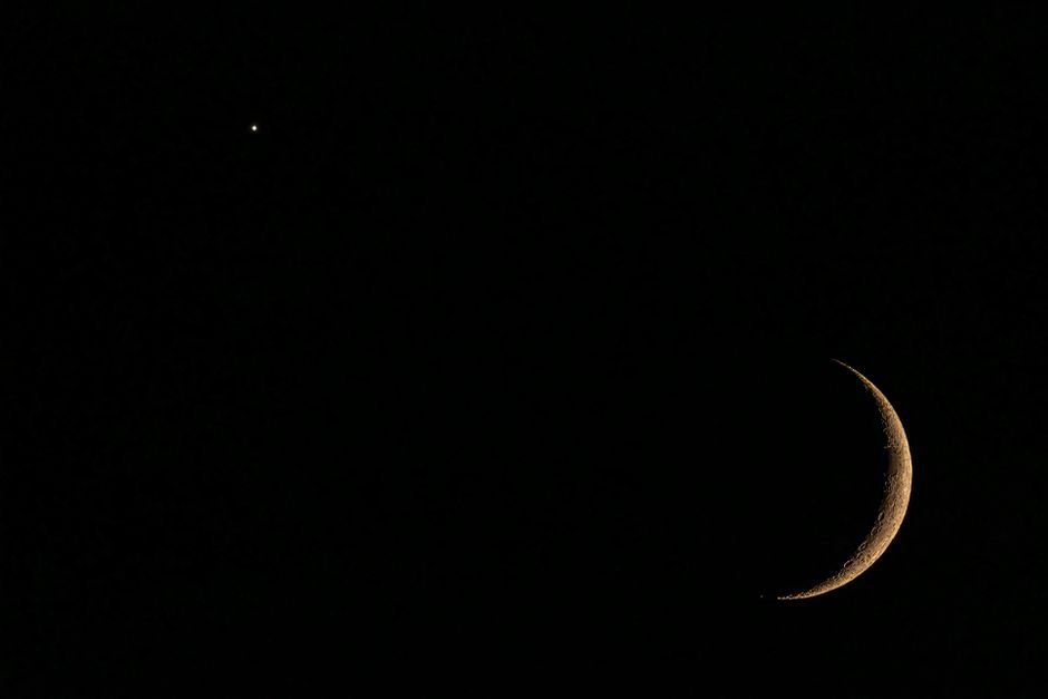 A striking view of a crescent moon and star against a dark night sky, capturing celestial beauty.