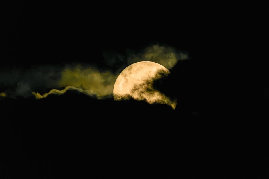 A captivating image of the full moon partially hidden by dark clouds at night.