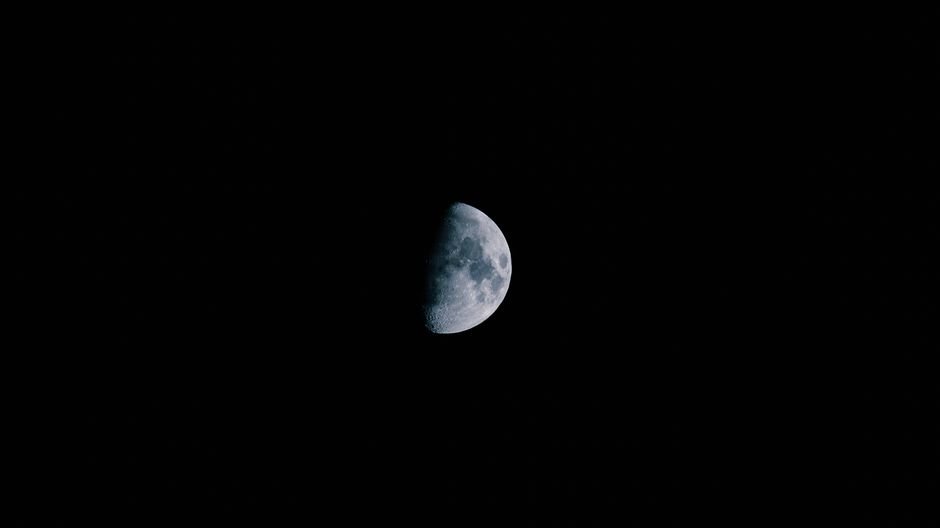 A detailed shot of the half moon against a pitch-black night sky.