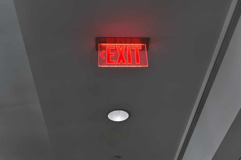 Close-up of a glowing red exit sign on a ceiling in an indoor environment.