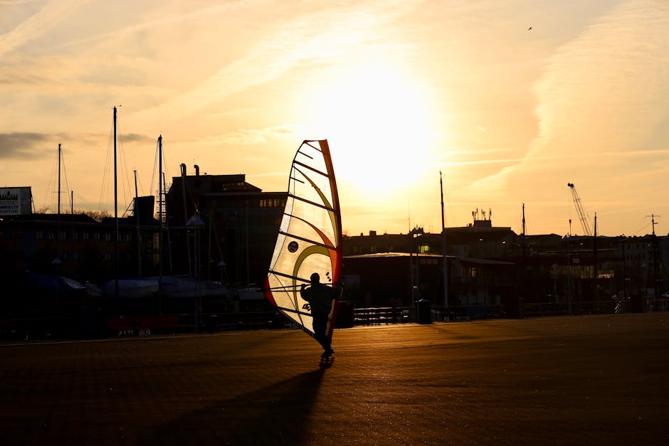 A windsurfer captures the sunset's glow in a city port, embodying freedom and adventure.