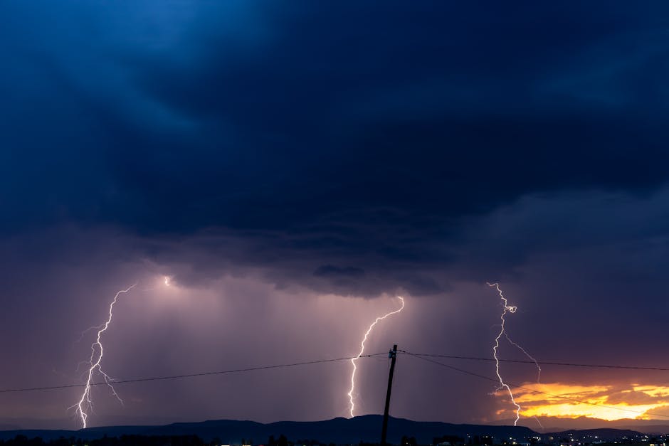 Lightning strikes illuminate a stormy night in Epangweni, South Africa with a vibrant sunset horizon.