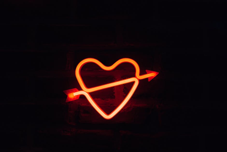 A glowing neon heart with an arrow on a dark background, perfect for romantic themes.