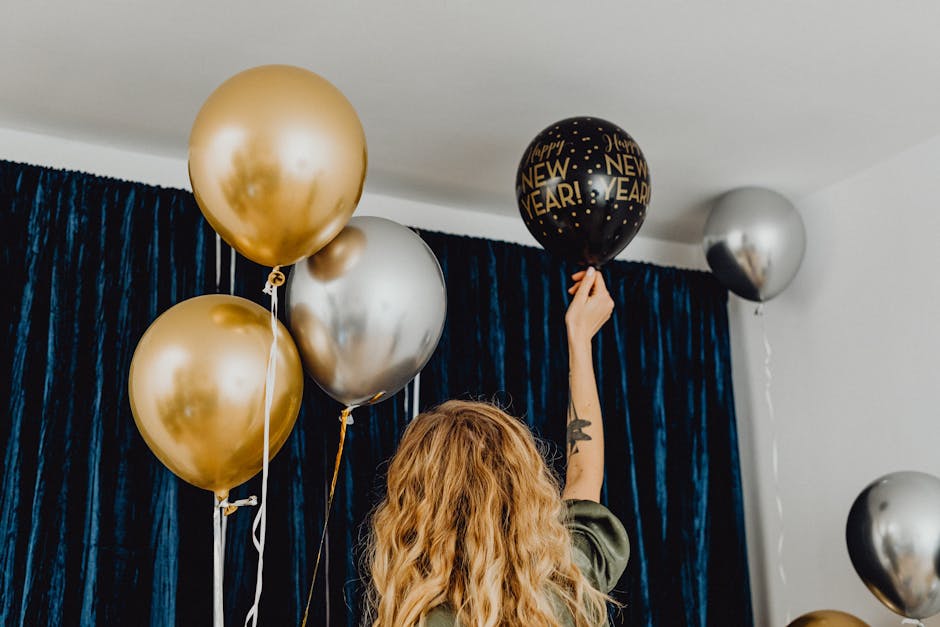 Woman preparing for a New Year party with gold and silver balloons indoors.