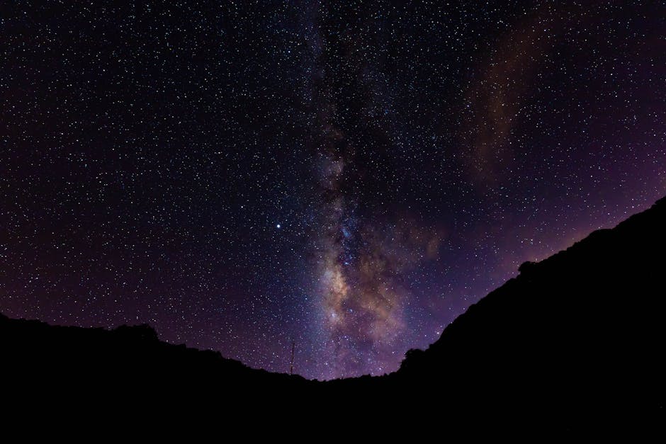A breathtaking view of the Milky Way illuminating the night sky over a mountain silhouette.