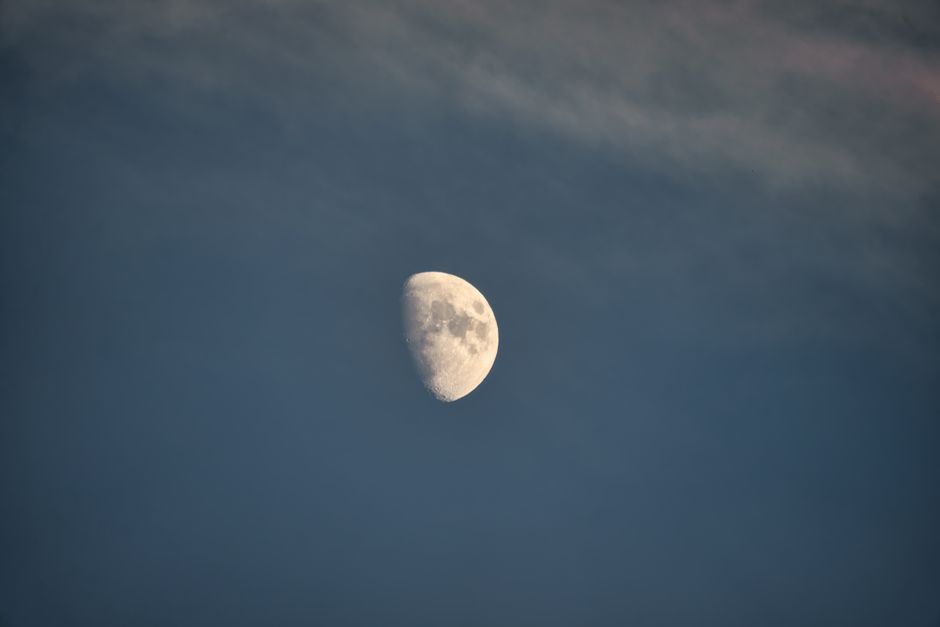 A serene half moon set against a partially cloudy night sky, creating a tranquil celestial scene.