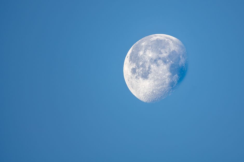 Scenery of waning gibbous moon shining on dark blue starless sky at night