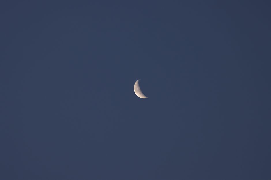 A serene view of the waning crescent moon against a clear evening sky in Jönköping, Sweden.