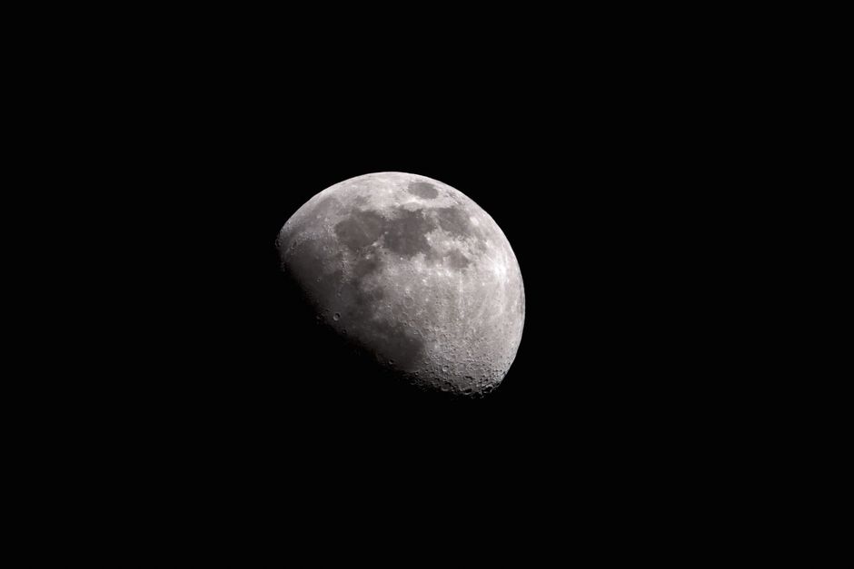 Black and white of moon with craters glowing on black sky at night