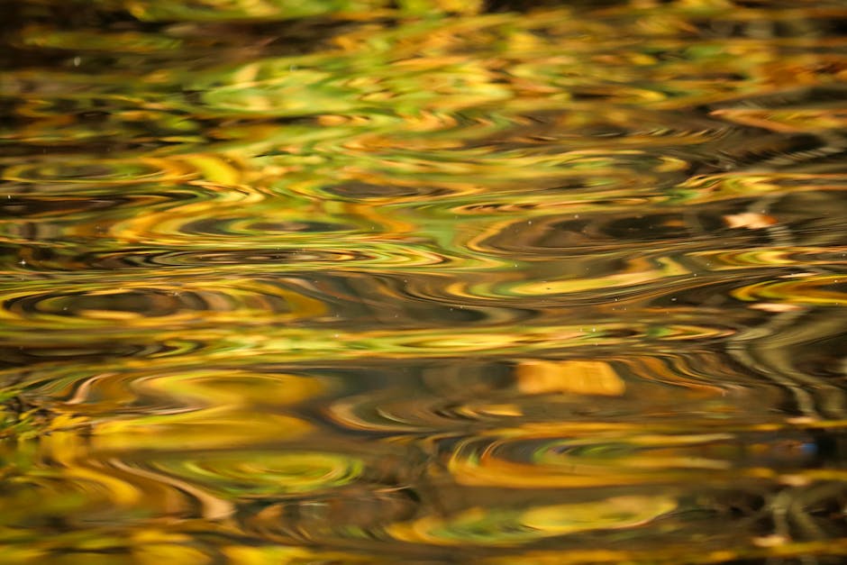 A mesmerizing close-up of golden water ripples reflecting autumn colors, creating an abstract pattern.