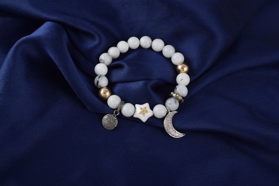 Luxury beaded bracelet with celestial charms on blue silk sheet.