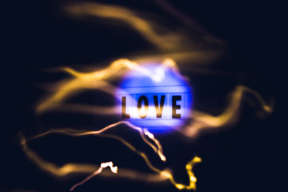 A conceptual abstract image featuring the word 'LOVE' illuminated with blue and yellow light streaks on a black background.