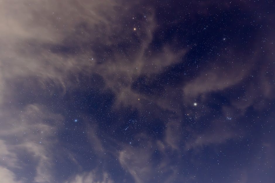 A mesmerizing view of a starry night sky with scattered clouds creating unique patterns.