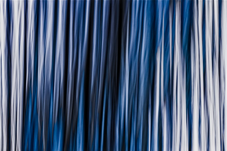 Dynamic abstract image featuring flowing blue vertical lines creating a soft, ethereal texture.