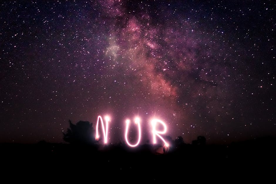 Night sky with stars and Milky Way galaxy featuring artistic light painting spelling 'NUR'.