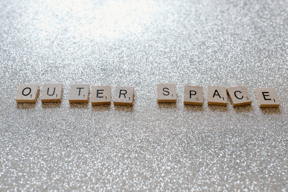 Scrabble tiles spelling 'Outer Space' on glittery surface, creative concept image.