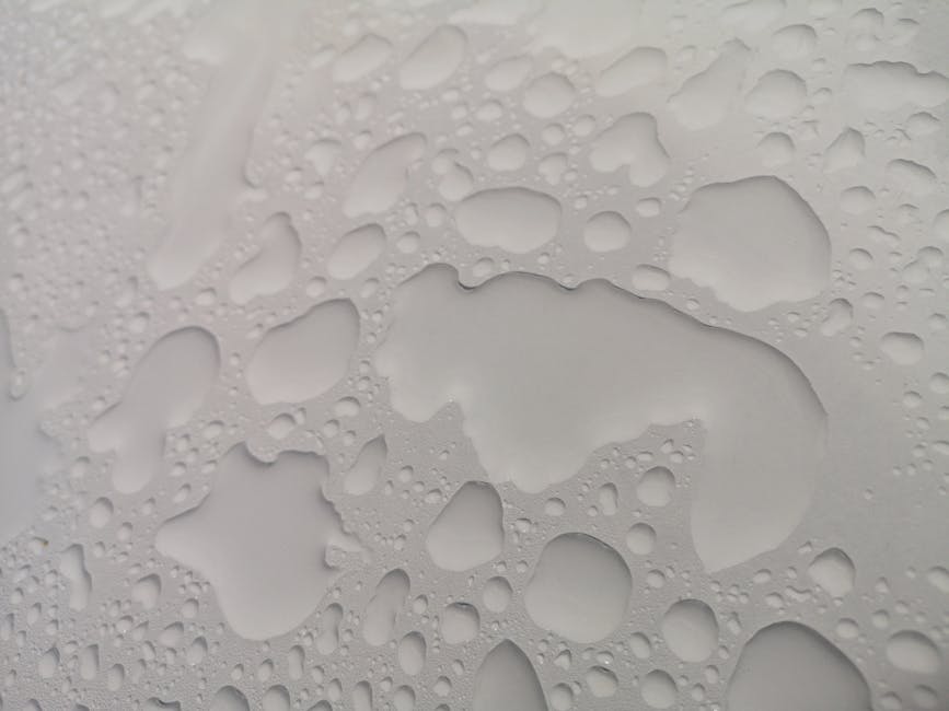 Detailed close-up of water droplets forming abstract patterns on a white surface.