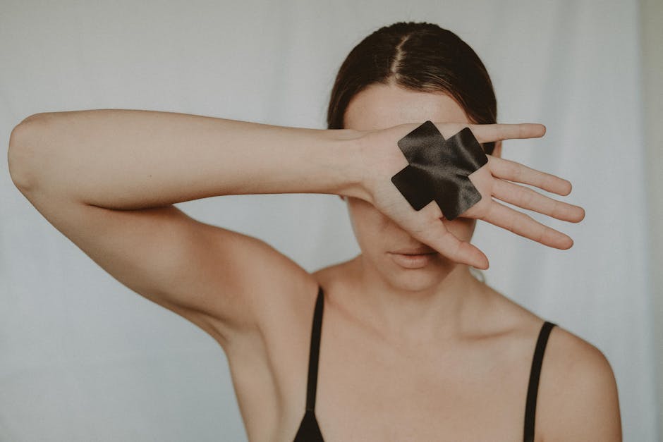 Faceless young lady in black underwear showing hand with black cross tape against abuse on white background