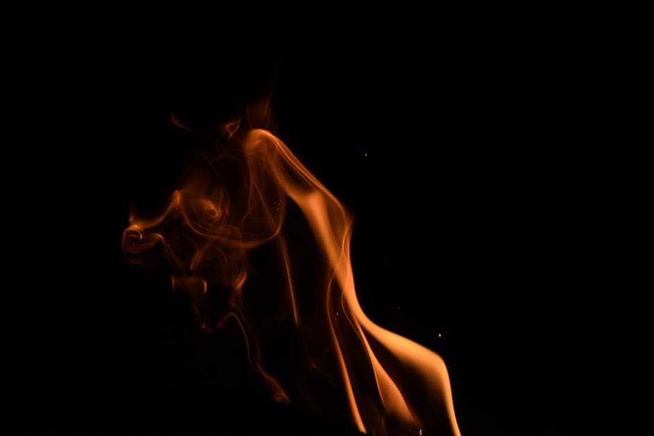 A captivating capture of an orange flame against a dark background, creating a dramatic and artistic effect.