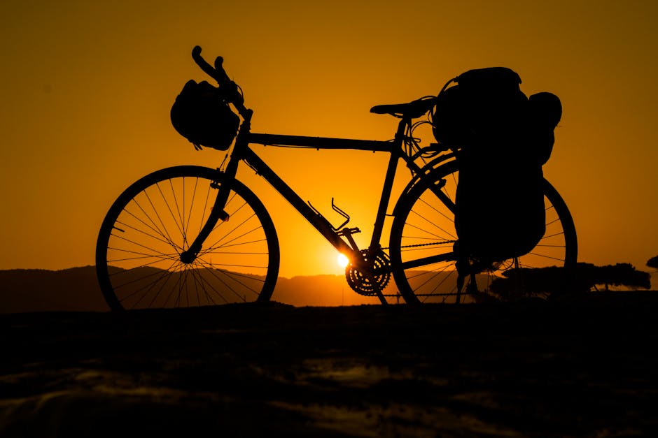 Silhouette of a bicycle against a vibrant sunset, evoking adventure and freedom.