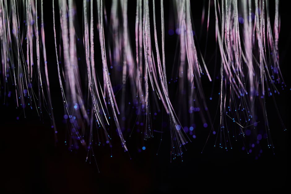 Abstract image of ethereal fiber optic strands cascading with glowing blue lights.