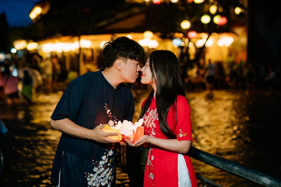 A couple shares an intimate moment holding lanterns at a vibrant night festival.