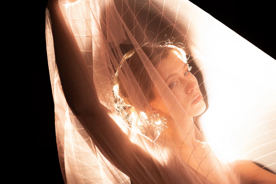 Artistic portrait of a woman illuminated through a delicate veil.