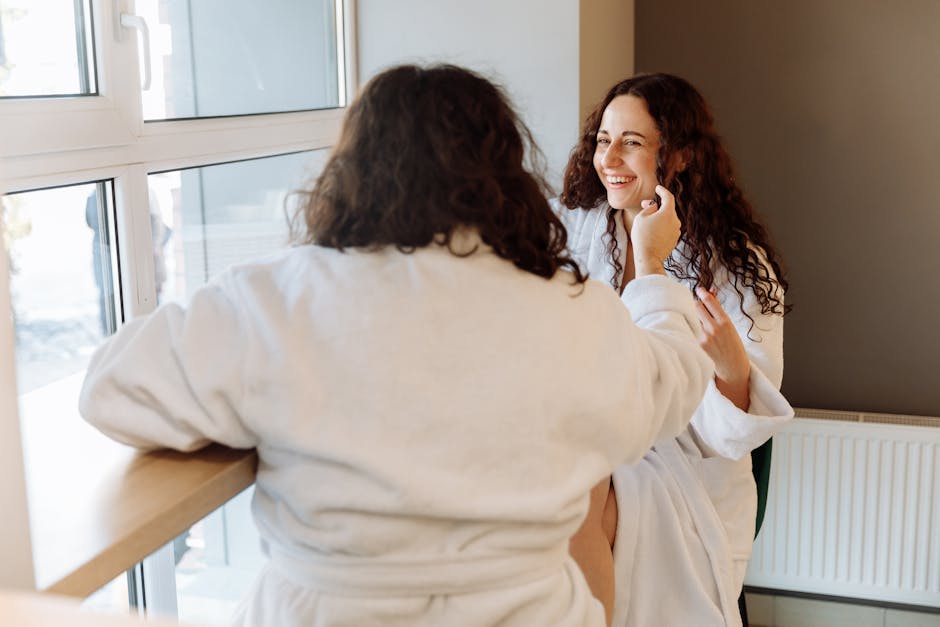 Two women laughing and enjoying a relaxed morning in bathrobes by the window.