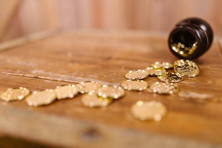 A close-up of scattered gold coins from a pot on a wooden table symbolizing St. Patrick's Day treasure.