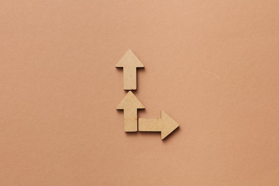 Three cardboard arrows arranged on a brown background, symbolizing direction and choice.