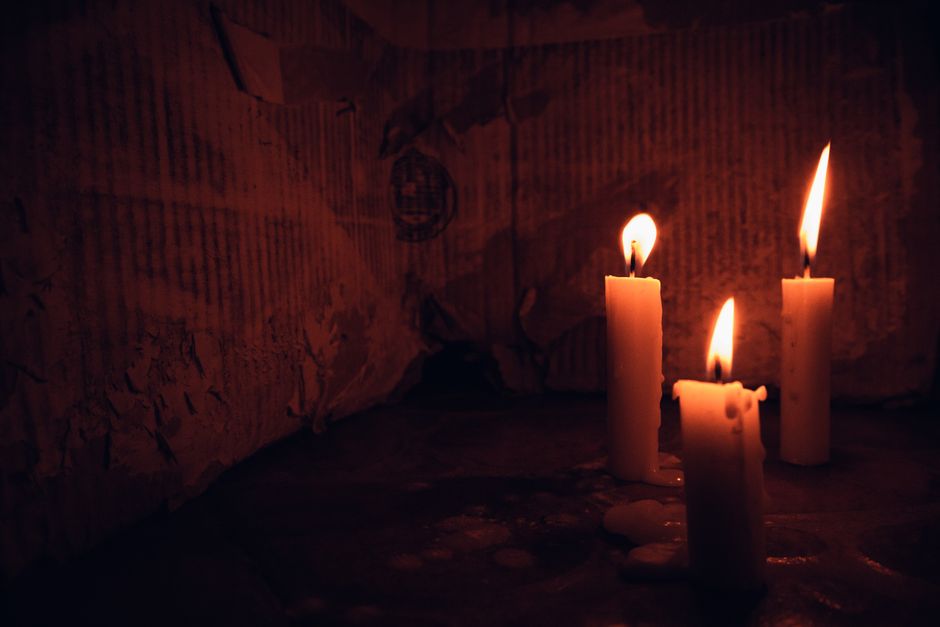 Three candles burn with a warm glow, creating a cozy ambiance in a dimly lit room.