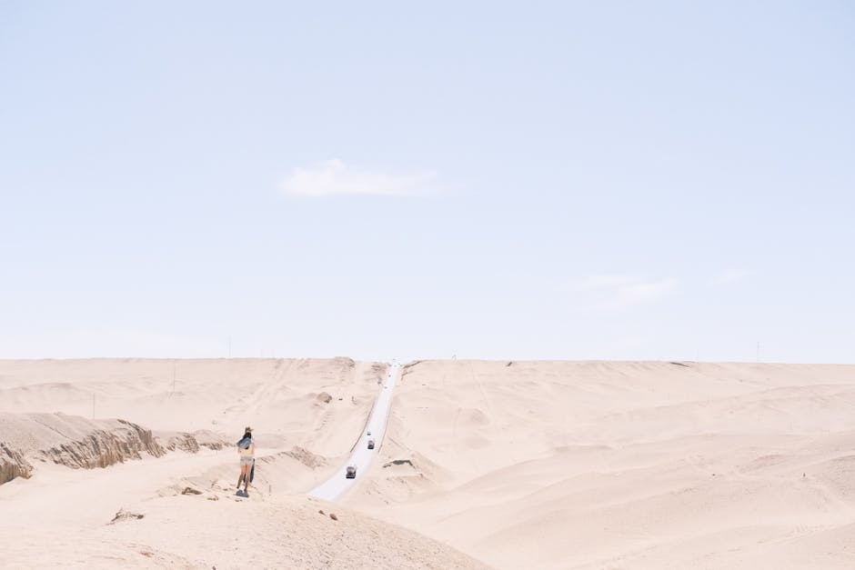 Expansive desert landscape with a solitary road leading towards the horizon under a bright sky.