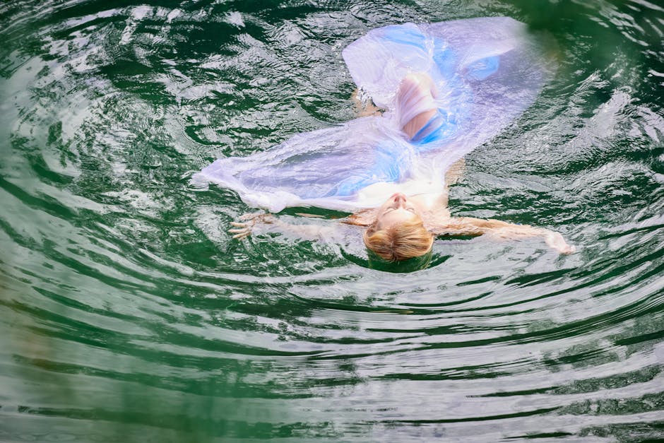A woman in a flowing dress floats gracefully in tranquil water, capturing a moment of relaxation.