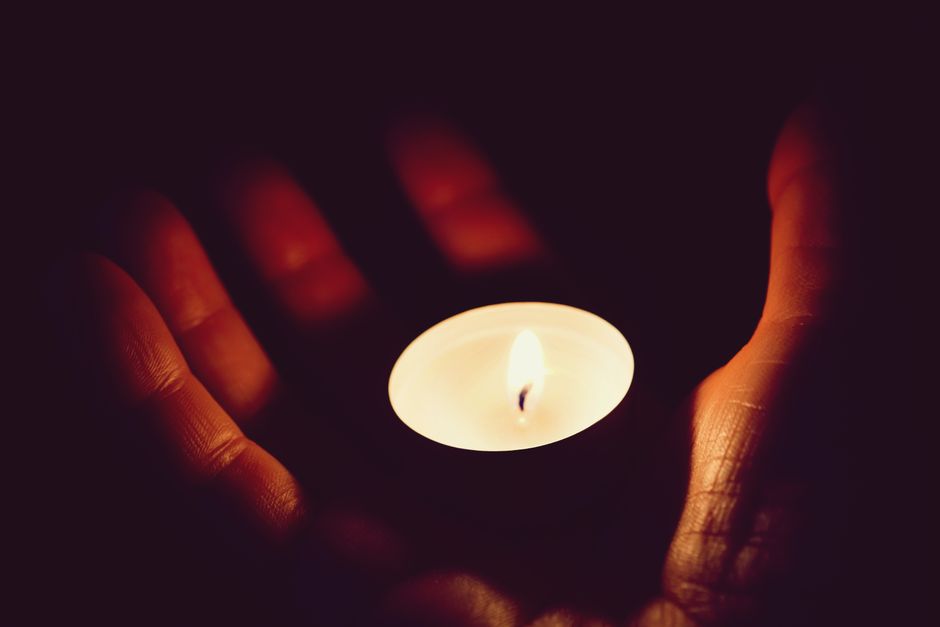 A serene image of hands gently holding a glowing candle, creating a warm and peaceful atmosphere.
