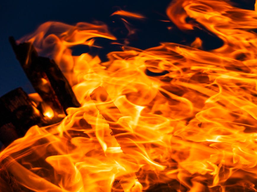 Close-up of vibrant flames during a nighttime campfire, highlighting intense heat and movement.